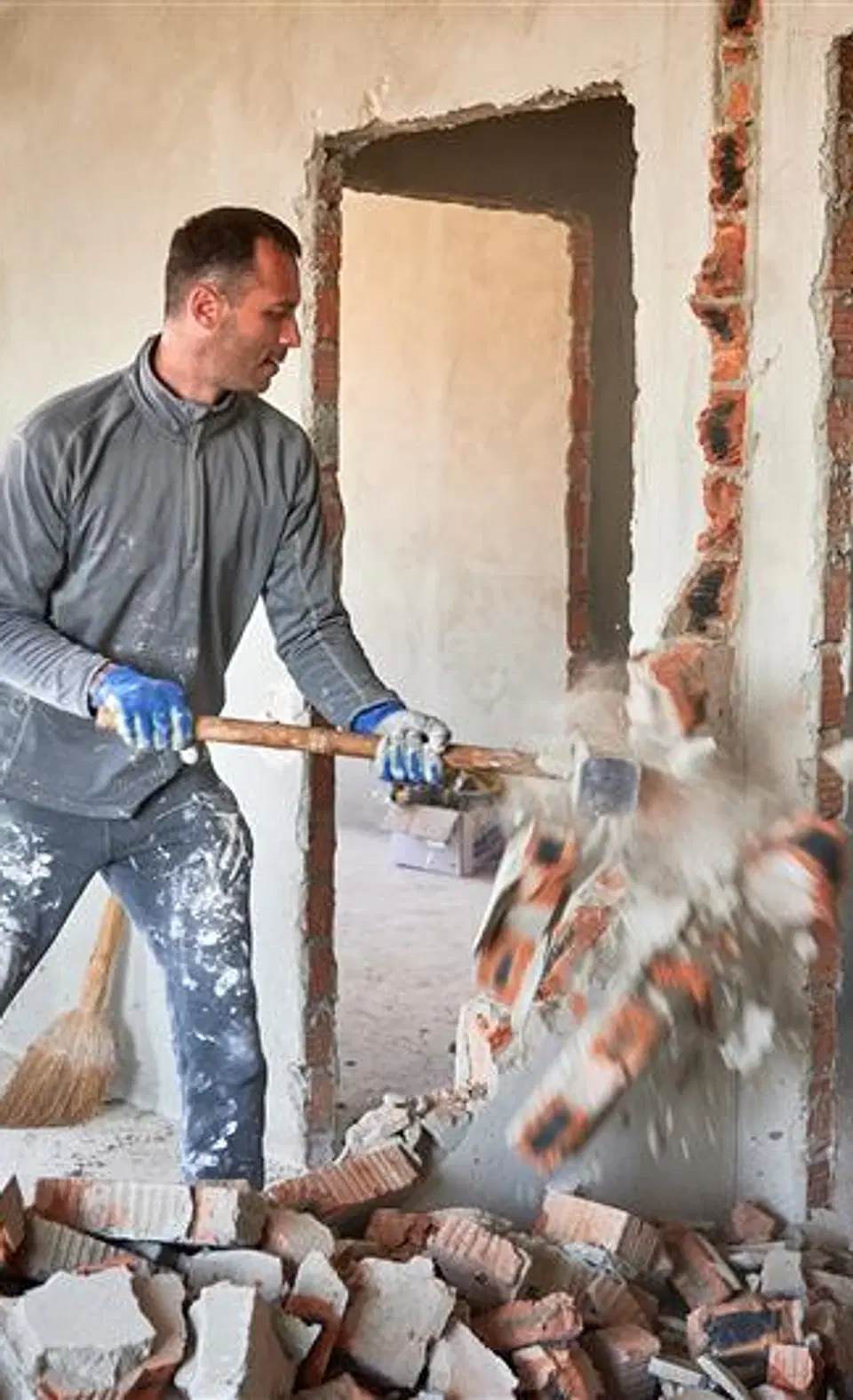 Tradesperson demolishing a wall during a renovation. Illustrative photograph, not a completed Ecobuild job.