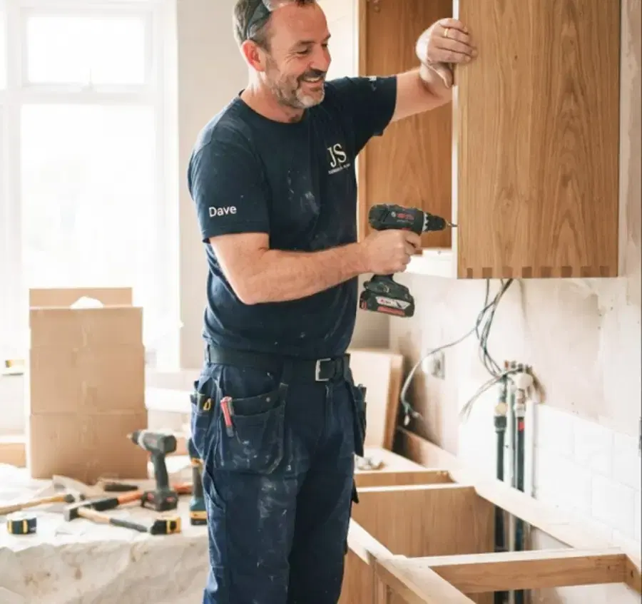 Tradesperson fitting kitchen cabinets. Illustrative photograph.