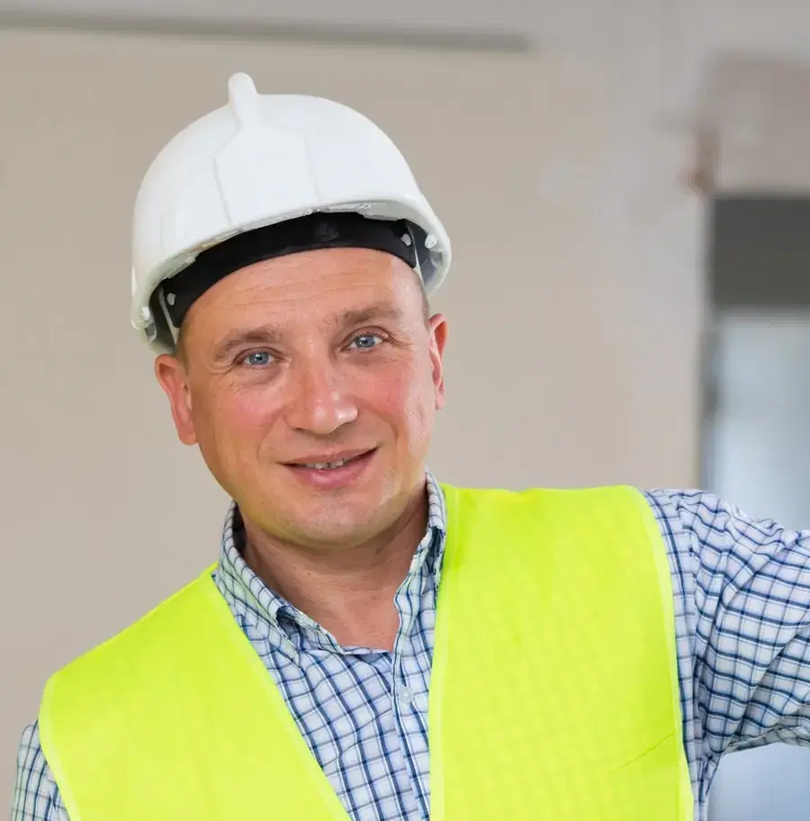 Smiling tradesperson in a hard hat and high-visibility vest. Illustrative photograph.